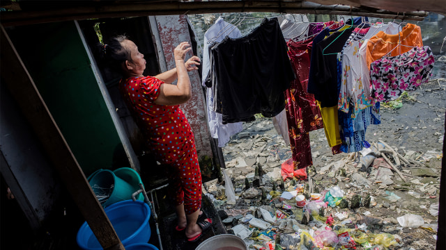 Seorang warga saat menjemur pakaian di kawasan padat penduduk di kanal Xuyen Tam, Kota Ho Chi Minh. (Foto: Kao Nguyen / AFP)