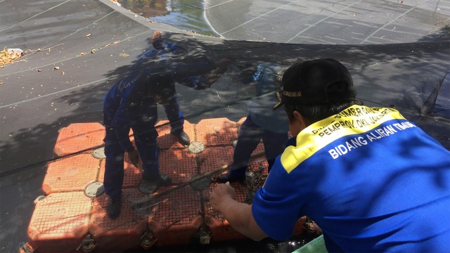 Petugas Sumber Daya Air (SDA) mencopot jaring yang sempat menutupi kali Item saat pergelaran Asian Games. (Foto: Fachrul Irwinsyah/kumparan)