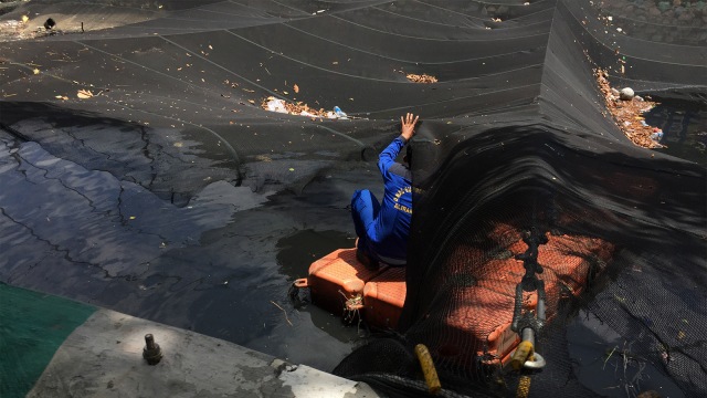 Petugas Sumber Daya Air (SDA) mencopot jaring yang sempat menutupi kali Item saat pergelaran Asian Games. (Foto: Fachrul Irwinsyah/kumparan)