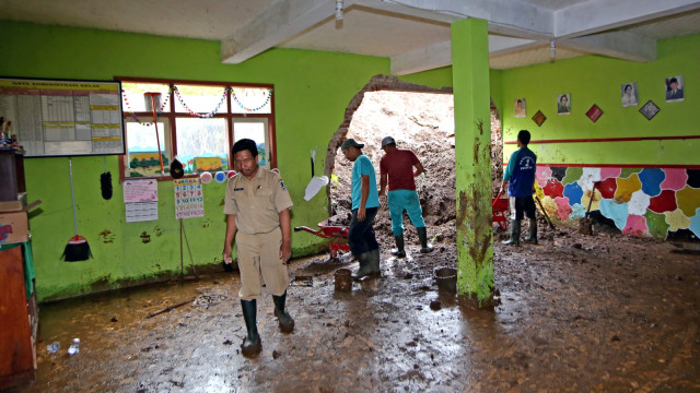 Guru bersama warga bergotong royong membersihkan tanah yang yang menerjang ruang kelas akibat longsor di MTs. Nahdlatuth Thullaab, Desa Jelun, Banyuwangi. (Foto: ANTARA FOTO/Budi Candra Setya)