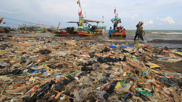 Nelayan menyandarkan perahunya di bibir pantai yang dipenuhi sampah plastik di Desa Dadap, Indramayu, Jawa Barat. (Foto: ANTARA FOTO/Dedhez Anggara)