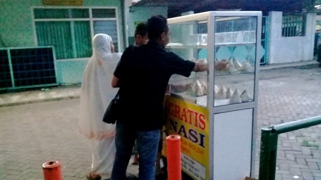 Masyarakat Surabaya mengambil makanan gratis yang tersedia di etalase kaca. (Foto: Phaksy Sukowati/kumparan)