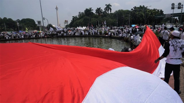 Sejumlah massa reuni 212 membentangkan bendera merah putih di sekitar patung kuda, Jakarta, Minggu (2/12/2018). (Foto: Irfan Adi Saputra/kumparan)