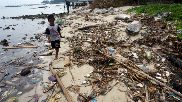 Seorang anak melintasi pinggir Pantai Pulau Pari yang dipenuhi sampah. (Foto: Iqbal Firdaus/kumparan)