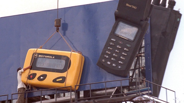 Seorang pekerja memasang replika pager berukuran besar di baliho di Phnom Penh, Kamboja (23/6/1998). (Foto: AFP PHOTO/David VAN DER VEEN)