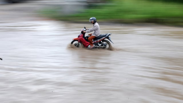 Pengendara menerobos banjir yang menggenangi Jalan Lintas Timur Sumatera di Telanaipura, Jambi, Selasa (4/12/2018). (Foto: Antara/Wahdi Septiawan)