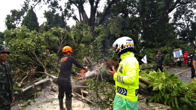 Sejumlah anggota polisi Polresta Kota Bogor membantu membersihkan batang pohon yang hancur akibat puting beliung di kota Bogor. (Foto: Dok. Polresta Kota Bogor)