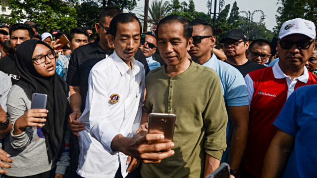 Presiden Joko Widodo (kanan) berfoto bersama  warga saat melakukan kunjungan di "Car Free Day" Bandung, Jawa Barat, Minggu (11/11/2018). (Foto: Antara/Raisan Al Farisi)