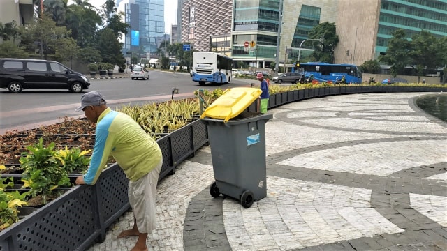 Petugas kebersihan membersihkan sisa-sisa sampah di kolam air mancur Bundaran HI. (Foto: Maulana Ramadhan/kumparan)
