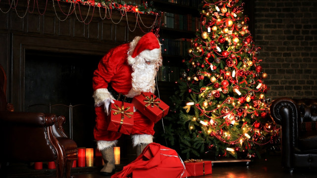 Santa Claus menaruh kado di bawah pohon Natal  (Foto: Shutter Stock )