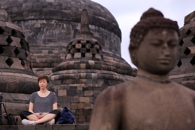 Seorang pengunjung yang sedang bermeditasi di Candi Borobudur (Foto: Aria Sankhyaadi/kumparan)