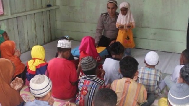 Seorang anggota kepolisian mengajarkan al-qur'an  kepada anak-anak di Kelurahan Malawele, Distrik Aimas, Sorong. (Foto: Mirsan Simamora/kumpara)