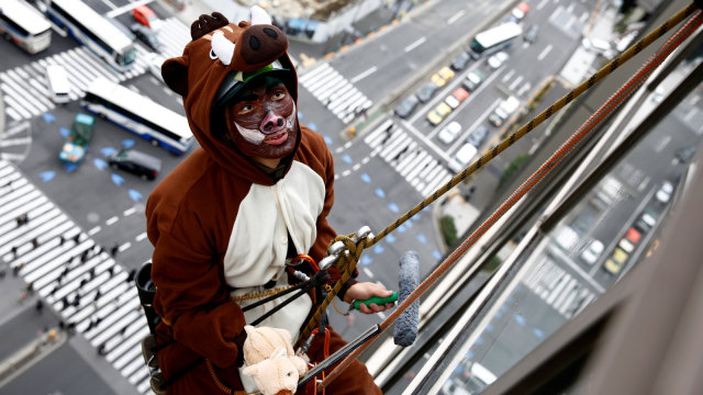 Pekerja berkostum babi hutan membersihkan jendela Hotel Ryumeikan, Tokyo, Jepang. (Foto: REUTERS/Kim Kyung-Hoon)