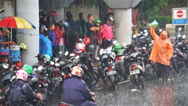 Beberapa warga sekitar memanfaatkan kesempatan ketika hujan untuk berjualan mantel hujan. (Foto: Iqbal Firdaus/kumparan)