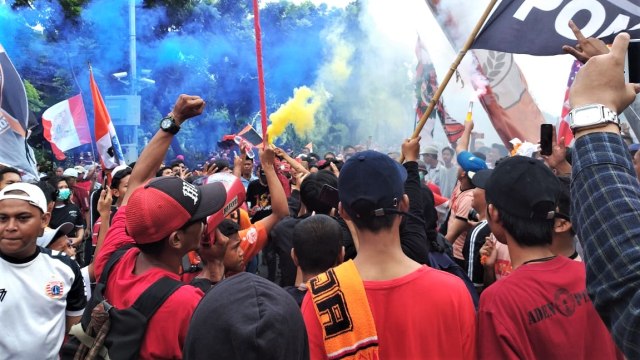 Para supporter Persija menyalakan suar saat pawai. (Foto: Paulina Herasmaranindar/kumparan)