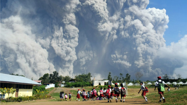 Anak-anak sekolah berjalan bersama di Sekolah Dasar Sipandak, Desa Tiga Pancur, Karo, Sumatara Utara, saat abu vulkanik yang berasal dari Gunung Sinabung (19/2/2018). (Foto: AFP/ANTO SEMBIRING)