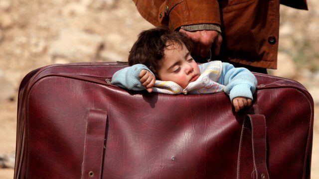 Seorang anak tertidur di dalam tas saat berada di Desa Beit Sawa, Ghouta Timur, Suriah (15/3/2018).   (Foto: REUTERS/Omar Sanadiki  )