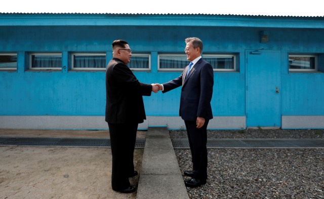 Pemimpin Korea Utara Kim Jon Un (kiri) bersalaman dengan Presiden Korea Selatan Moon Jae In (kanan) di garis perbatasan militer Korea Utara dan Korea Selatan (27/4/2018). (Foto: Photo by Korea Summit Press Pool / Korea Summit Press Pool / AFP)