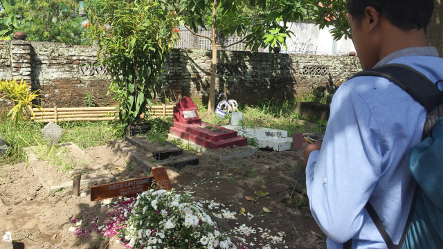 Seorang wartawan mengunjungi Pemakaman Umum Jambon Purbayan yang geger dengan kabar dipotongnya nisan salib. (Foto: Arfiansyah Panji Purnandaru/kumparan)