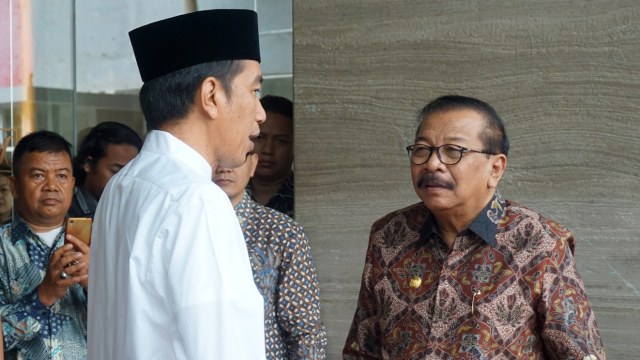 Gubernur Jatim, Soekarwo (kanan) berbincang dengan Presiden Joko Widodo yang akan bertolak ke Madura. (Foto: Yudhistira Amran Saleh/kumparan)