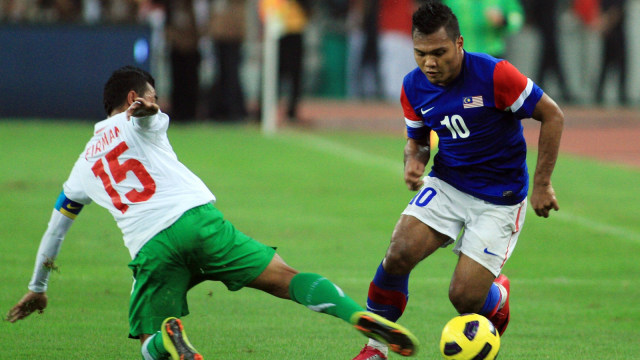 Safee Sali (kanan) melewati Firman Utina pada laga final Piala AFF 2010 antara Malaysia dan Indonesia. (Foto: Kamarul Akhir/AFP)