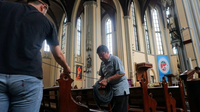 Sejumlah petugas membersihkan kursi serta memasang kabel-kabel yang akan digunakan saat Hari Raya Natal. Petugas lain dibantu umat Kristiani ikut mendekorasi bagian luar Gereja Katedral, Jakarta, Sabtu (22/12). (Foto: Nugroho Sejati/kumparan)