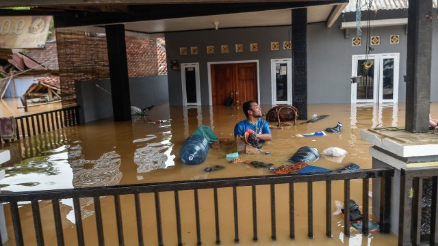 Warga berada di halaman rumahnya yang terendam banjir di kampung Sentul, Desa Sukarame, Labuan, Banten, Rabu (26/12/2018). (Foto: ANTARA FOTO/Muhammad Adimaja)
