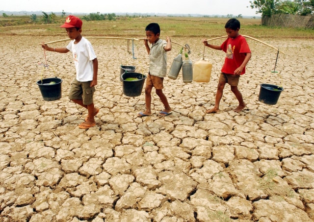 Tiga orang anak membawa air yang diambil dari salah satu sungai yang tersisa di Cibarusa pada September 2002 lalu. Indonesia adalah salah satu negara yang rentan mengalami krisis air, terutama di musim kemarau. AFP PHOTO/Weda (Foto: Weda/AFP Photo)