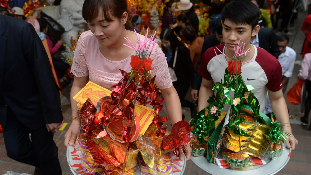 Sejumlah orang membawa nampan penuh persembahan saat berjalan ke kuil Ba Chua Kho di provinsi utara Bac Ninh dalam rangka tahun baru Vietnam, Tết. (Foto: AFP/HOANG DINH NAM)