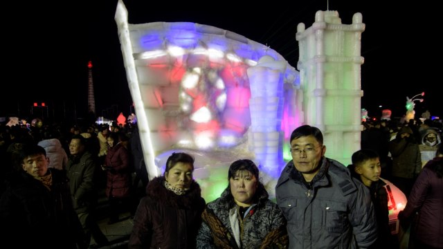 Sejumlah orang berfoto  di depan patung es menyambut tahun baru di lapangan Kim Il Sung,Pyongyang, Korea Utara. (Foto: KIM Won Jin / AFP)