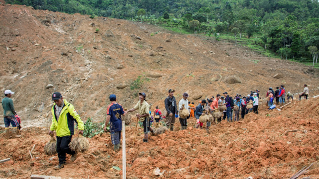 Sejumlah warga bergotong royong memindahkan padi dari lokasi tanah longsor di kampung adat Sinarresmi, Cisolok, Kabupaten Sukabumi, Jawa Barat, Selasa (1/1/2019). (Foto: ANTARA FOTO/Nurul Ramadhan)