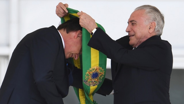Mantan Presiden Brasil Michel Temer (kanan) menyerahkan selempang kepresidenan kepada presiden baru Brasil Jair Bolsonaro di Istana Planalto (Foto: AFP/ EVARISTO SA)