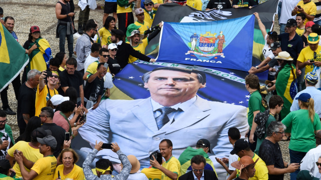 Para pendukung membawa poster raksaksa bergambar Presiden baru Brasil Jair Bolsonaro. (Foto: AFP/EVARISTO SA)