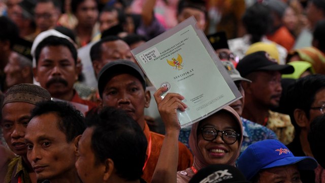 Warga menunjukkan sertifikat tanah miliknya saat penyerahan sertifikat tanah untuk rakyat di Surabaya oleh Presiden Jokowi, Kamis (6/9/2018).  Foto: ANTARA FOTO/Zabur Karuru
