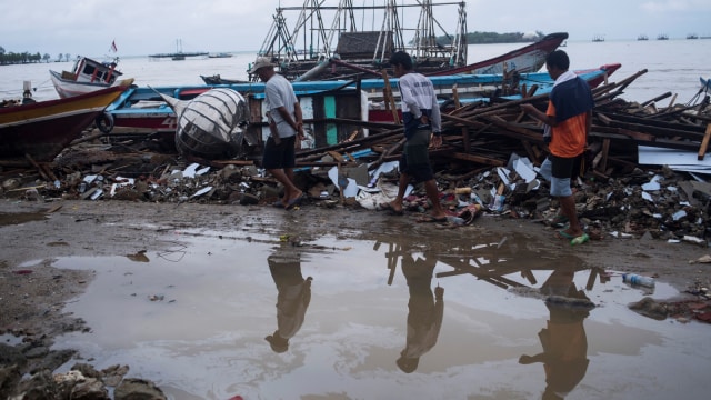 Warga berjalan di sisa-sisa bangunan dan kapal yang rusak diterjang tsunami Selat Sunda di Sumur, Pandeglang, Banten, Kamis (3/1).  (Foto: ANTARA FOTO/Sigid Kurniawan)