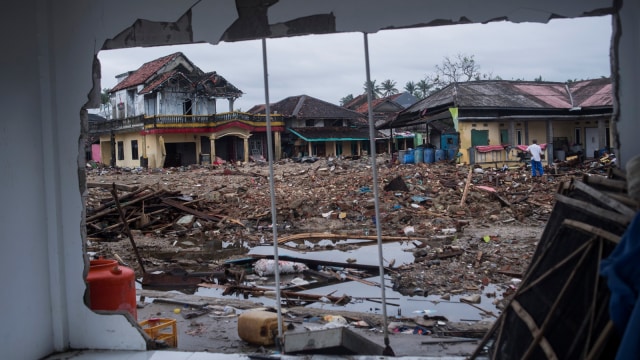 Warga berjalan di sisa-sisa bangunan yang rusak diterjang tsunami Selat Sunda di Sumur, Pandeglang, Banten, Kamis (3/1).  (Foto: ANTARA FOTO/Sigid Kurniawan)