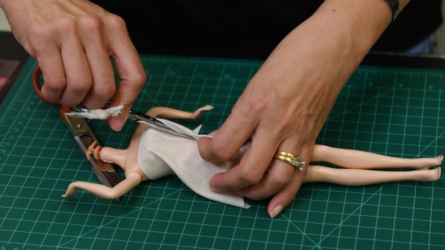 Desainer Carlyle Nuera memakaikan pakaian pada boneka Barbie di El Segundo, California, Amerika Serikat. (Foto:  AFP/Mark RALSTON)