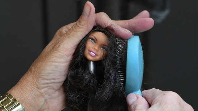 Seorang desainer merapihkan rambut boneka Barbie di El Segundo, California, Amerika Serikat. (Foto:  AFP/Mark RALSTON)