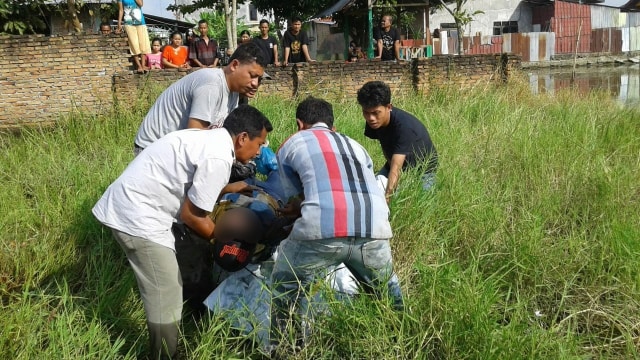 Warga mengangkat jasad korban yang ditemukan tewas di areal pesawahan Percut Sei Tuan. (Foto: Dok. Istimewa)