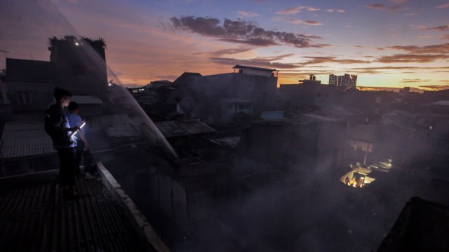 Warga melihat permukiman penduduk yang terbakar di kawasan Tambora, Jakarta, Kamis (3/1).  (Foto: ANTARA FOTO/Muhammad Adimaja.)