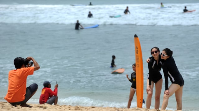 Turis berlibur di Pantai Kuta, Bali, Jum'at (4/1/2019).
 (Foto: AFP/SONNY TUMBELAKA)