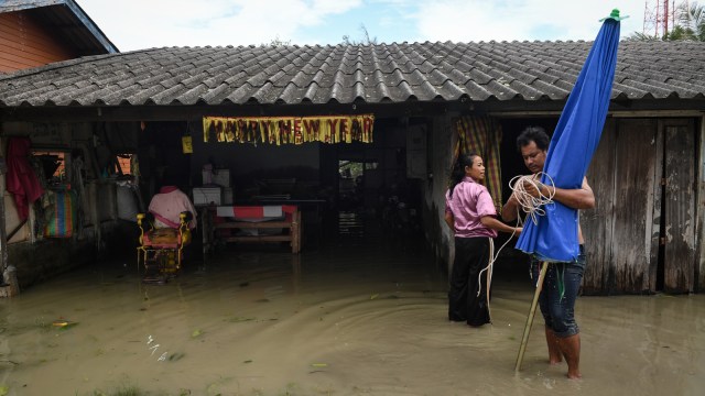 Sejumlah warga sedang memperbaiki rumah yang telah direndam banjir, setelah badai pabuk di Nakhon Si Thammarat, Thailand (5/6/2019). (Foto: AFP/Lillian SUWANRUMPHA)