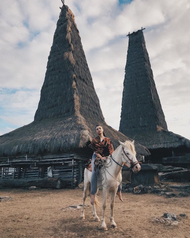 Tak sekadar wisata alam, Angela pun menikmati Sumba lengkap dengan kain, kuda, dan rumah adatnya (Foto: Instagram/Angela Panari)