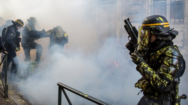 Sejumlah petugas polisi Perancis berada di tengah gas air mata saat terjadi bentrokan dengan demonstran "Rompi Kunging", Toulouse, Prancis, pada Sabtu (5/1/2019). (Foto: AFP/PASCAL PAVANI )