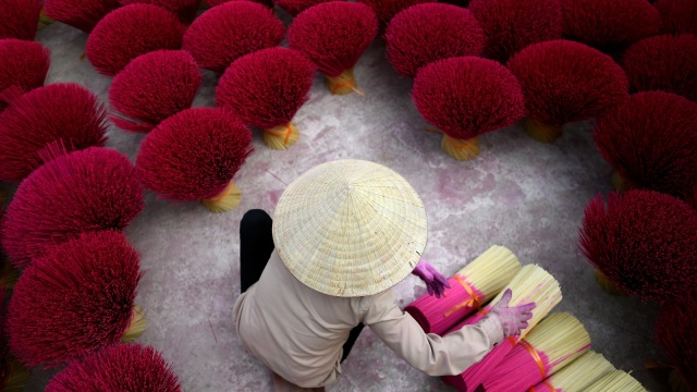 Seorang pekerja sedang mengeringkan batang bambu yang telah diproses, Desa Quang Phu Cau, Hanoi, Vietnam. (Foto: AFP/Manan VATSYAYANA)