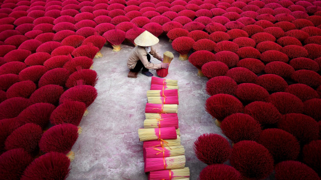 Seorang pekerja sedang mengeringkan batang bambu yang telah diproses, Desa Quang Phu Cau, Hanoi, Vietnam. (Foto: AFP/Manan VATSYAYANA)