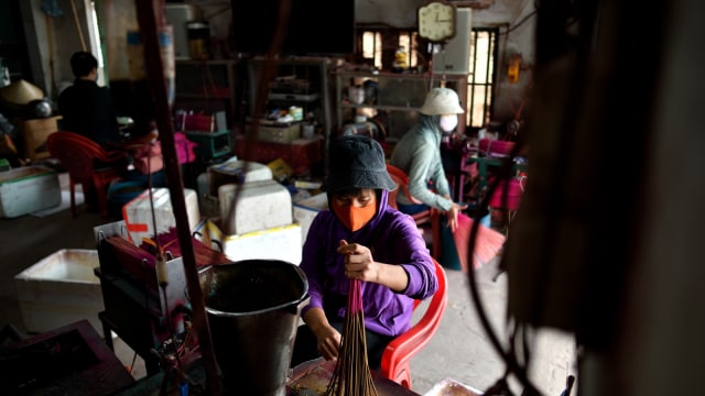 Para pekerja mempersiapkan batang bambu untuk diproses menjadi dupa, Desa Quang Phu Cau, Hanoi, Vietnam. (Foto: AFP/Manan VATSYAYANA)