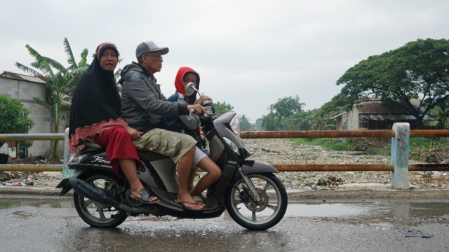 Pengendara sepeda motor yang melintas di atas jembatan Kali Pisang Batu, Bekasi. (Foto: Iqbal Firdaus/kumparan)