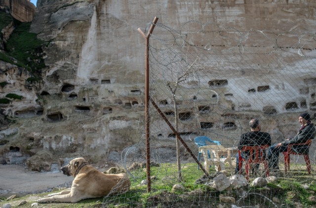 Dua orang warga duduk dihadapan gua bersejarah di Hasankeyf, Turki. (Foto: AFP/BULENT KILIC)