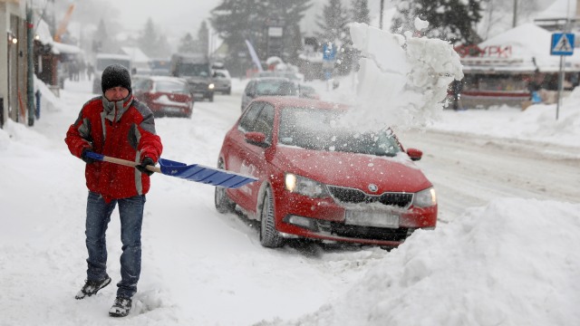 Seorang lelaki menyingkirkan salju dari trotoar di Szczyrk, Polandia.
 (Foto: REUTERS / Kacper Pempel)